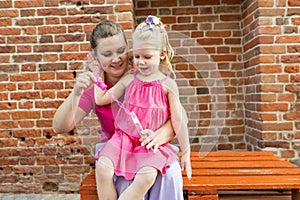 Blonde little girl with cochlear implant playing with her mother outdoor. Hear impairment deaf and health concept