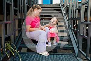 Blonde little girl with cochlear implant playing with her mother outdoor. Hear impairment deaf and health concept