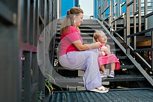 Blonde little girl with cochlear implant playing with her mother outdoor. Hear impairment deaf and health concept