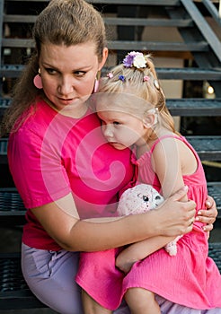 Blonde little girl with cochlear implant playing with her mother outdoor. Hear impairment deaf and health concept