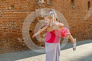 Blonde little girl with cochlear implant playing with her mother outdoor. Hear impairment deaf and health concept