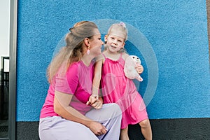 Blonde little girl with cochlear implant playing with her mother outdoor. Hear impairment deaf and health concept