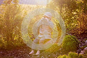 Blonde little toddler child with binoculars, sitting in garden on sunset