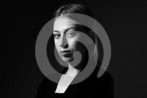 Blonde with long hair in a black suit on black background, black and white. Business woman