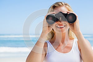 Blonde looking through binoculars on the beach