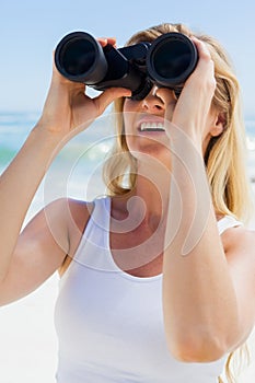 Blonde looking through binoculars on the beach