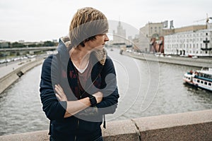 Blonde man is standing on the bridge in Moscow