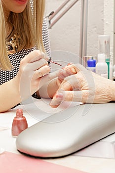 Blonde manicurist polishing fingernails