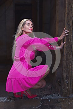 Blonde mature 40s woman in pink dress squat on timber