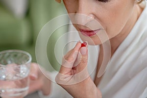 Blonde midaged woman feeling bad and taking a pill