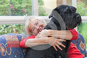 Blonde middle-aged woman is embracing the dog