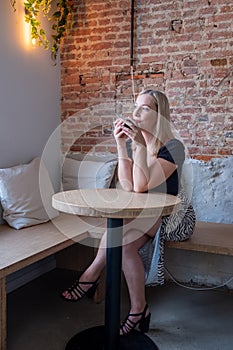 Blonde Millennial Woman Enjoying Coffee in Cafe