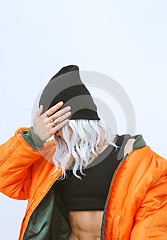 Blonde model in fashion urban street outfit. Trendy orange bomber jacket and stylish beanie cap. Fall winter seasons lookbook