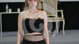 Blonde model girl in transparent dress walks on defile podium. Fashion catwalk.