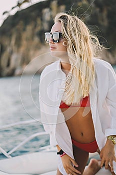 Blonde model with a red bikini and sunglasses on a boat ride