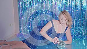 blonde model woman in a sequin blue dress on the background of New Year sequins rain, photo shoot at the photographer