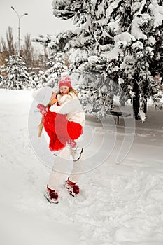Blonde mom in bright clothes holds her daughter in her arms against the background of a winter landscape