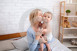 Blonde mother kissing her adorable little kid