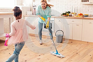Blonde mother mopping the floor and dancing with daughter