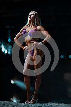 blonde muscular female bikini fitness champion posing