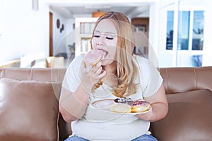 Blonde obesity woman eats donuts
