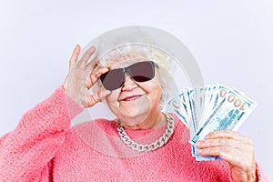 blonde old lady wear pinl sweater and sunglasses showing money isolated white background