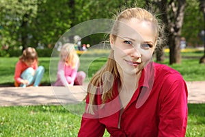 Blonde in park with playing children on background photo