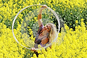 Blonde peasant girl in floral print dress on the rapeseed field