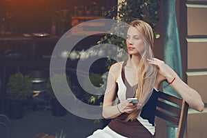 Blonde pensive beautiful girl using smart phone