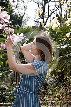 blonde with pleasure inhales an aroman of magnolia flowers standing under a tree