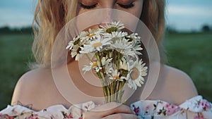 Blonde pretty young woman holds a bouquet of daisies