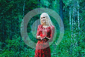 A blonde in a red dress with a red heart of thread in her hands