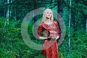 A blonde in a red dress in the woods