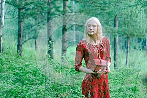 A blonde in a red dress in the woods