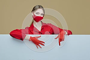 Blonde in red gloves and a mask poses with a large blank Billboard