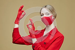 Blonde in red gloves and a mask shows the OK sign. the concept of preventing coronavirus covid 19