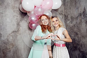 Blonde and redhead. Two young charming girlfriends at the party.