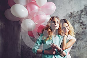 Blonde and redhead. Two young charming girlfriends at the party.