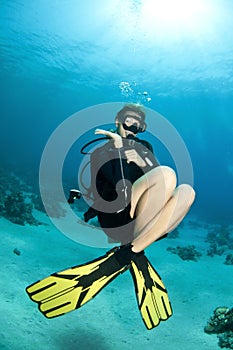 Blonde scuba diver swims in clear blue water