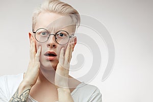 Blonde shocked man with wide opened mouth and bugged eyes shouting with horror.