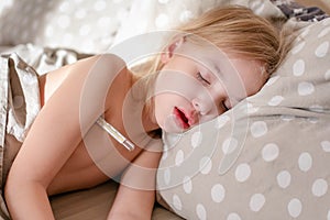 Blonde sleeping child with clinical thermometer