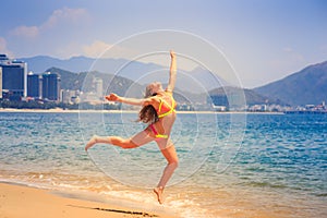 blonde slim girl in bikini jumps on beach