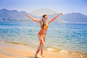 Blonde slim girl in bikini jumps on beach