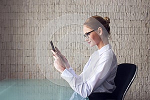 Blonde smart businesswoman working on tablet