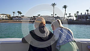 Blonde Smiling Girl With Boy, Close Up, Ride a Boat on the Canal, in the Background of Palms. The Concept of a Happy Family.