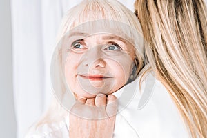 Blonde smiling grandmother gently hugging granddaughter.