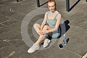 blonde sportswoman in tight activewear sitting