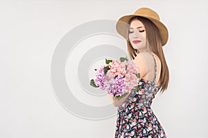 Blonde in a straw hat and dress with a bouquet of flowers