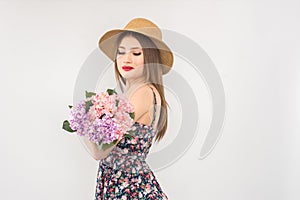 Blonde in a straw hat and dress with a bouquet of flowers