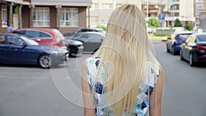 Blonde in a summer suit posing in the parking lot. Camera wiring. Women`s walk